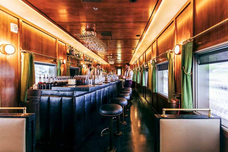 A cocktail bar with bartenders on either side of the bar.