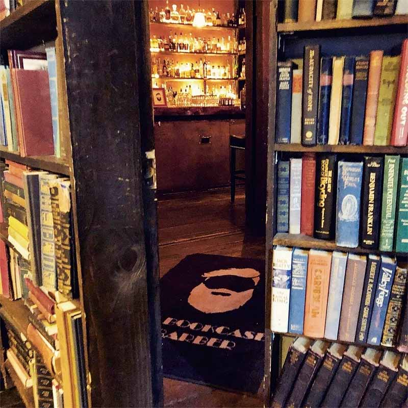 A book-shelf that opens into a bar.
