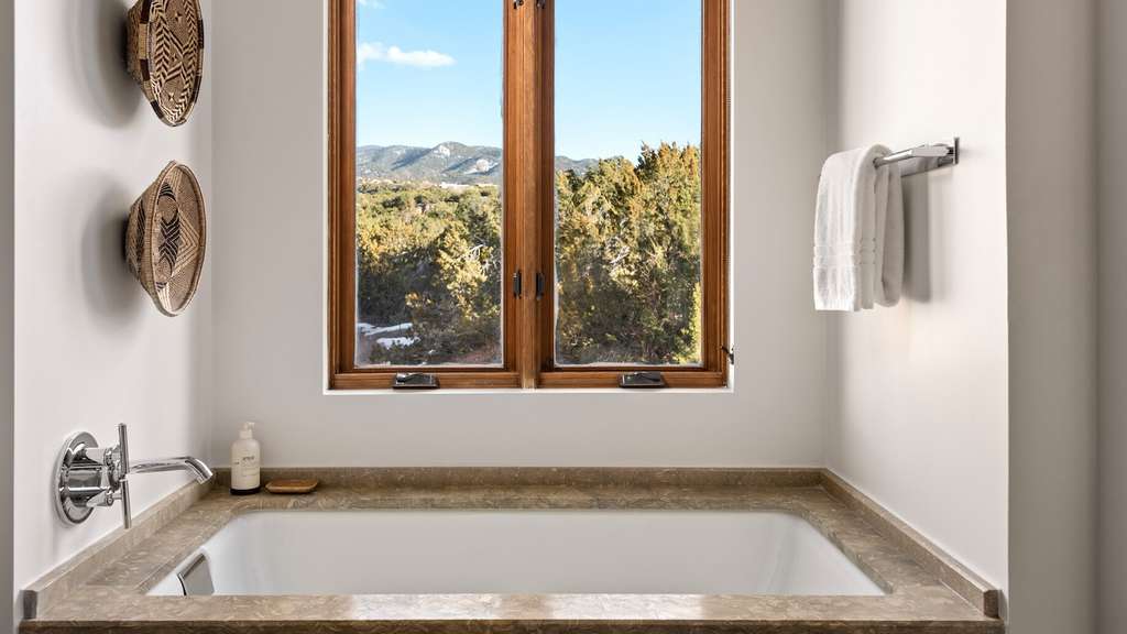 A bathtub and large windows offering views of the natural landscape.