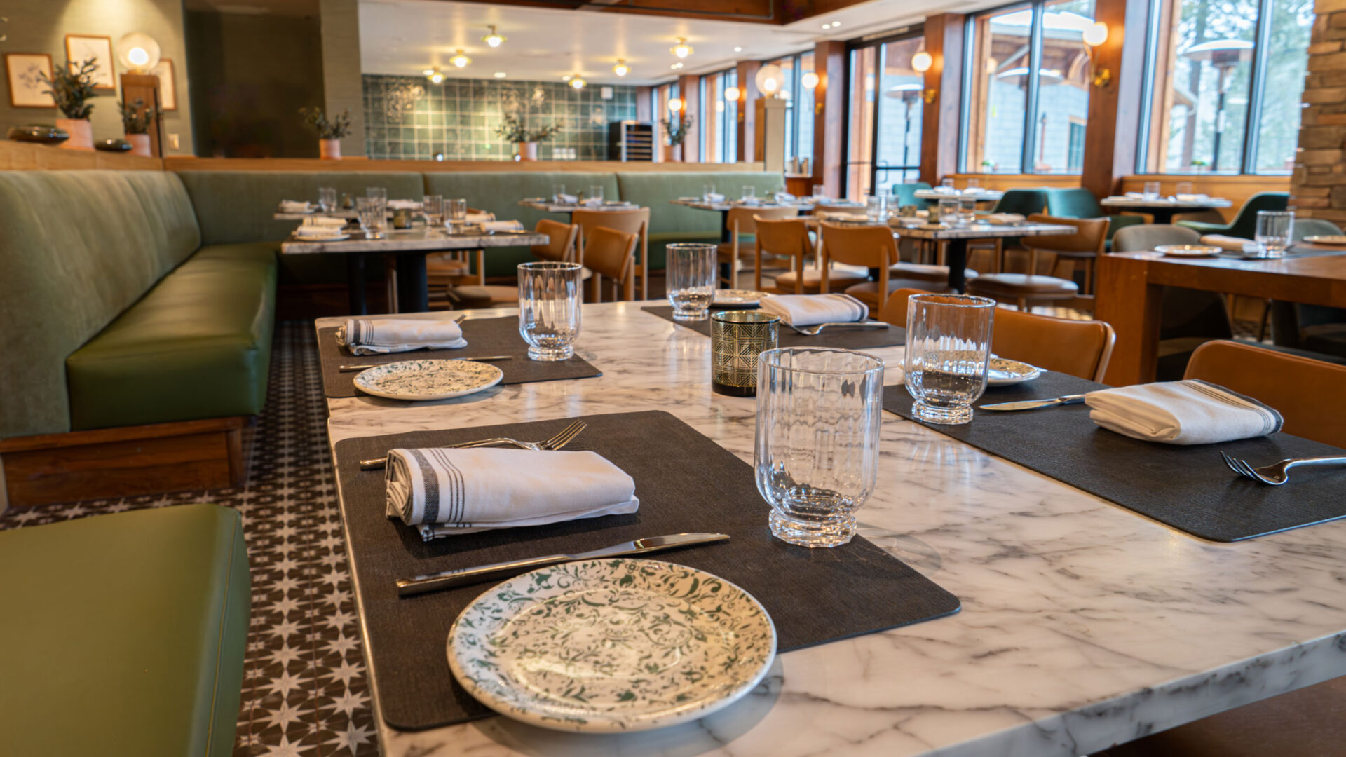 A restaurant featuring tables set for a meal, with green furniture.