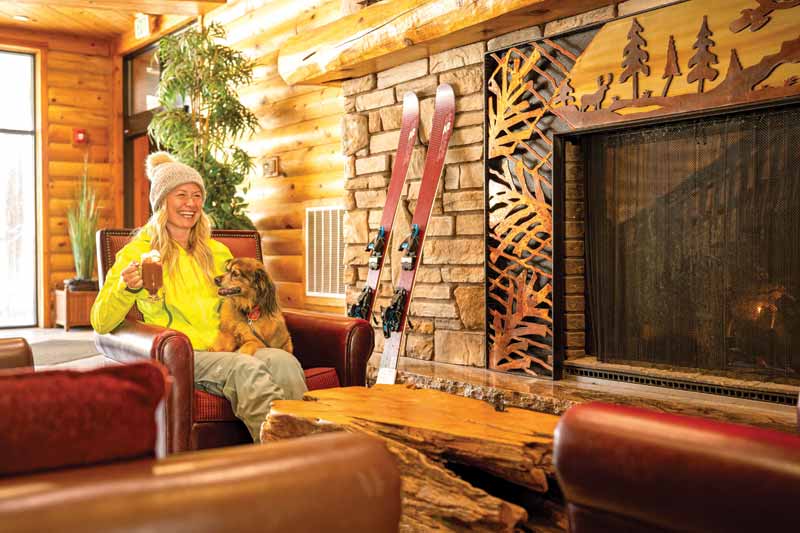 A woman with a beverage in her hand and her dog on her lap at the Brian Head Resort.