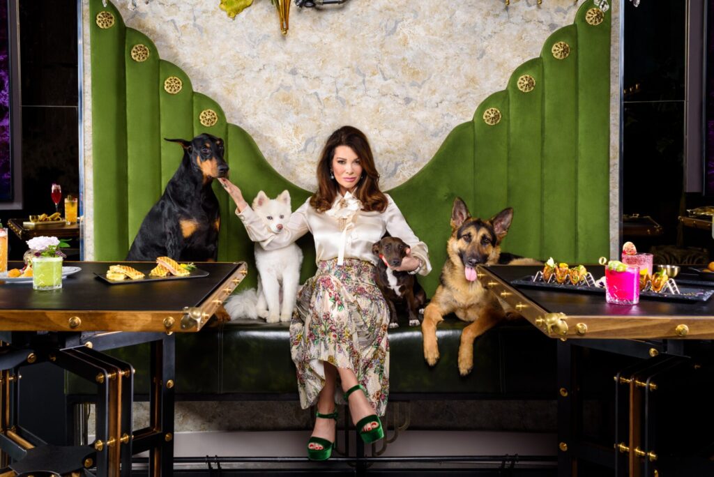 Lisa Vanderpump at Vanderpump Cocktail Garden posing for a photograph with dogs. 