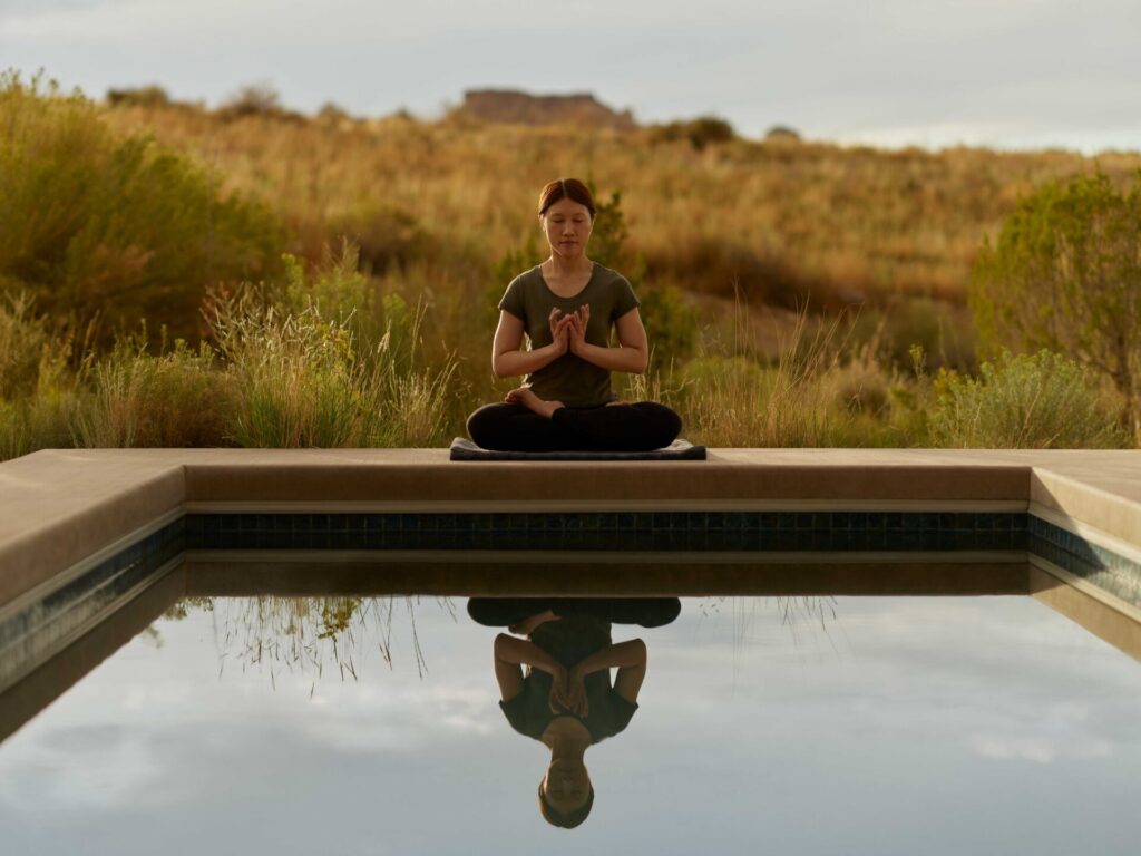A person meditating near a pool. 