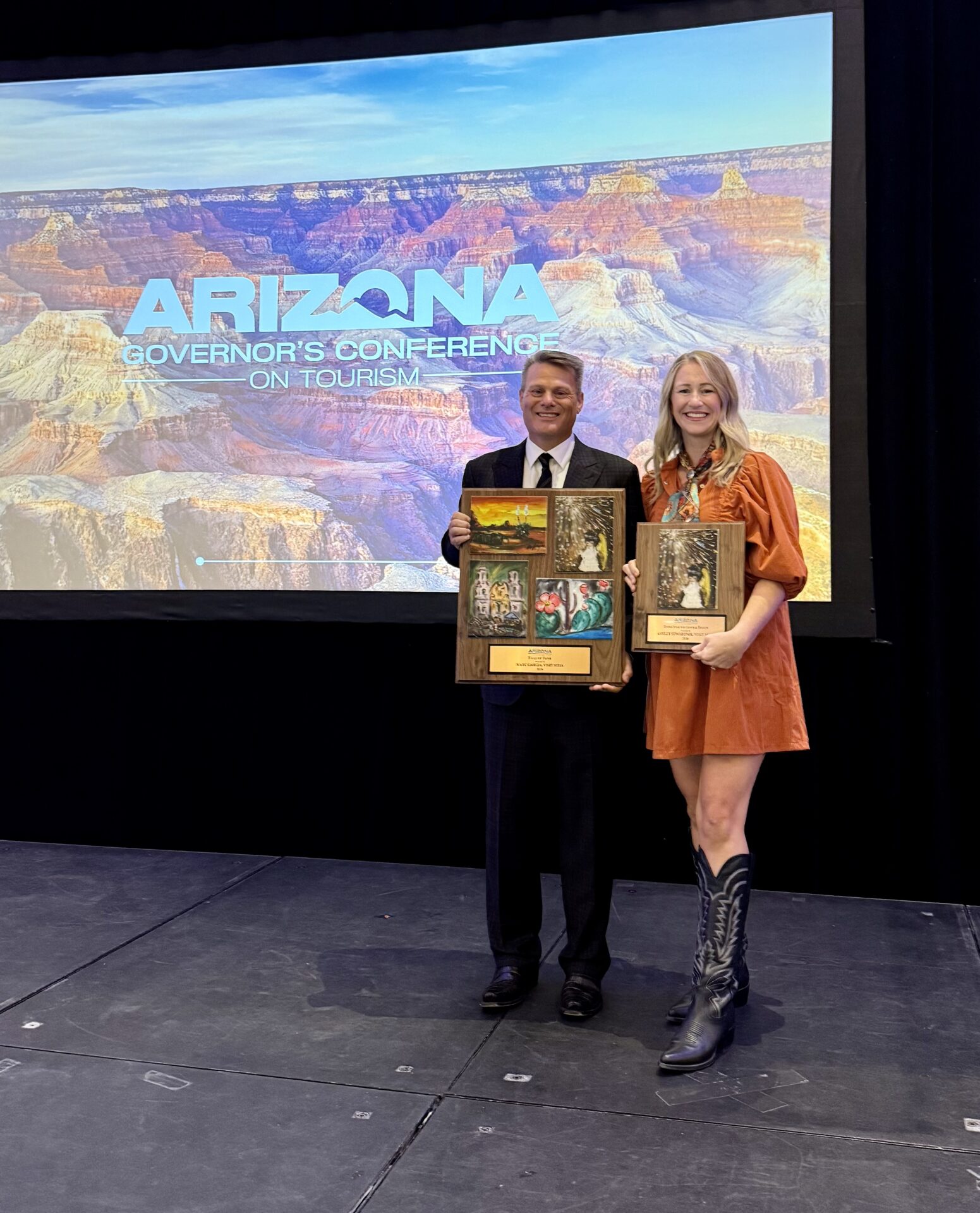 Visit Mesa President and CEO Marc Garcia and multimedia producer Ashley Stwertnik hold their awards at the Arizona Governor’s Conference on Tourism.