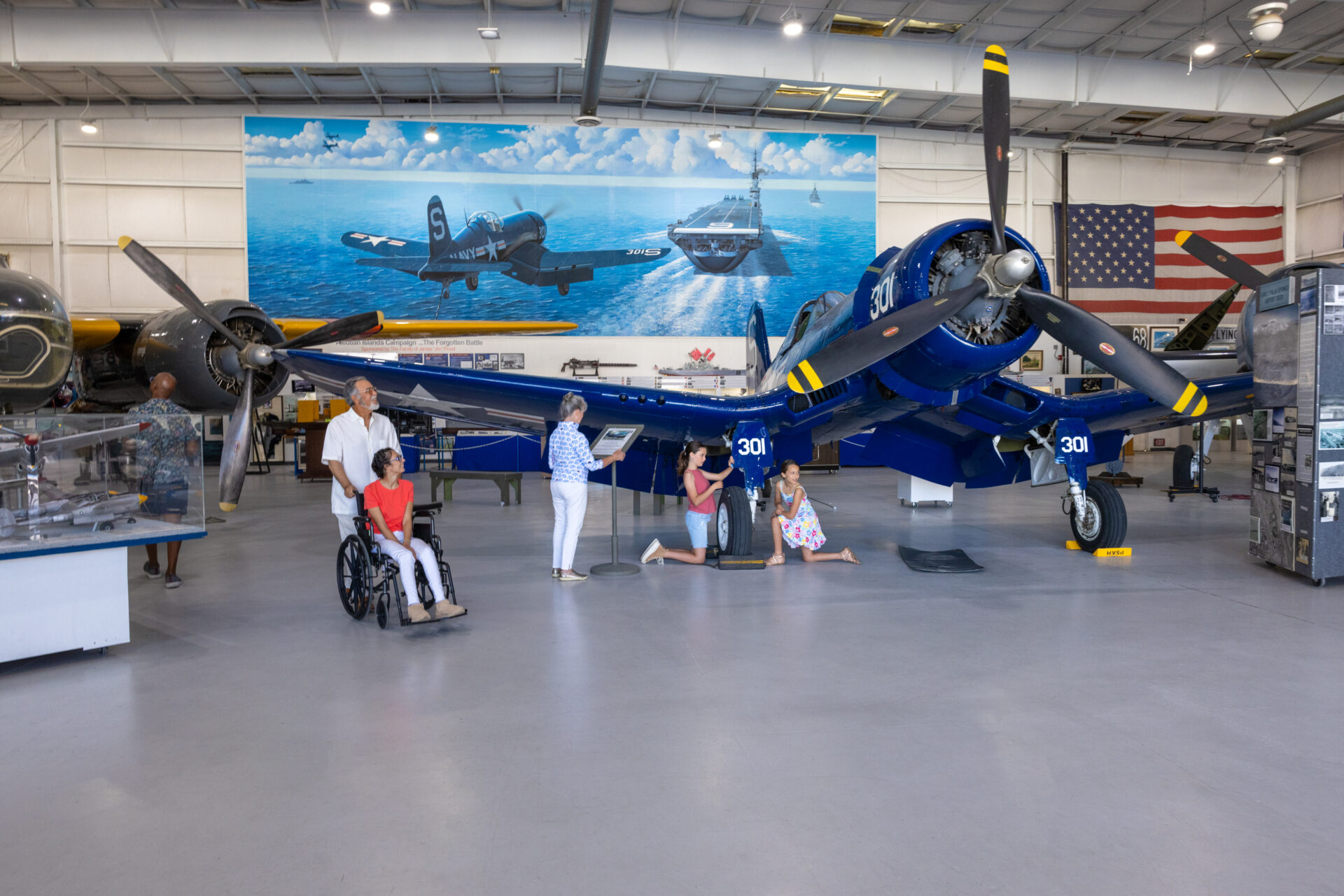 Visitors, including a woman using a wheelchair, explore vintage aircraft displays at the Palm Springs Air Museum.